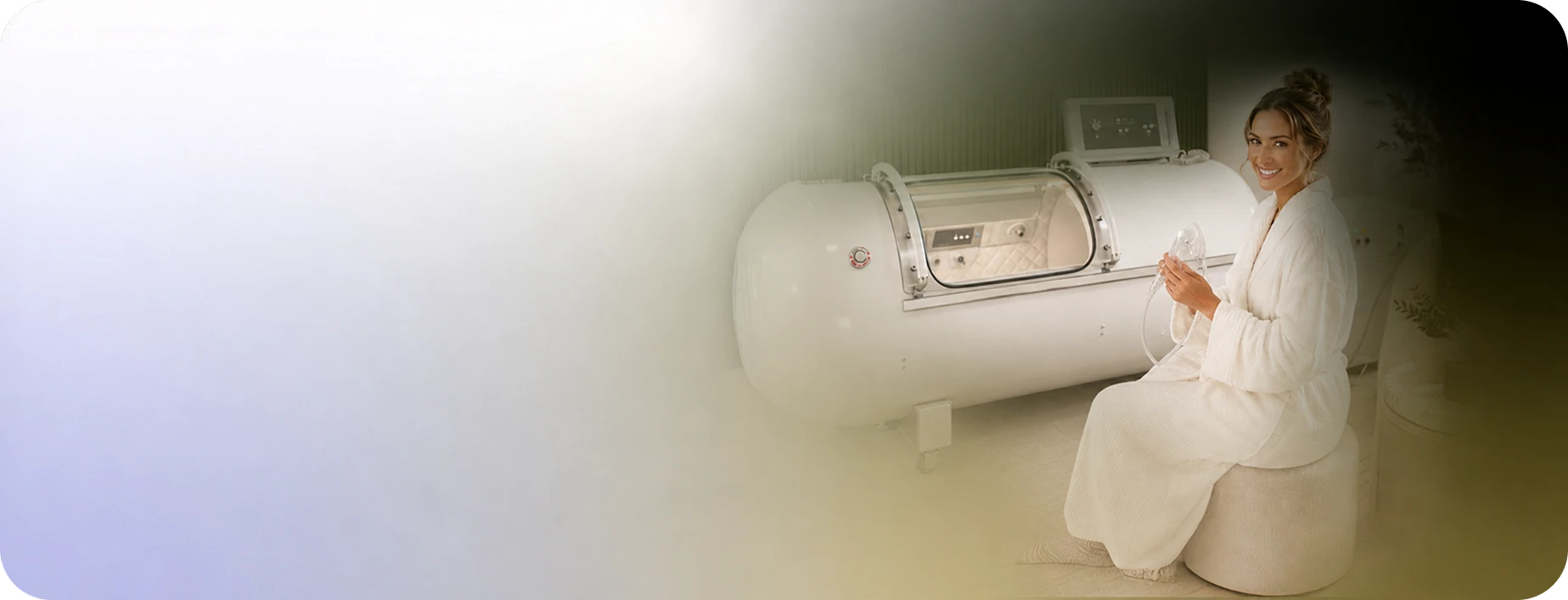 A guest in a robe beside the hyperbaric oxygen chamber at Restore Body & Mind Studio