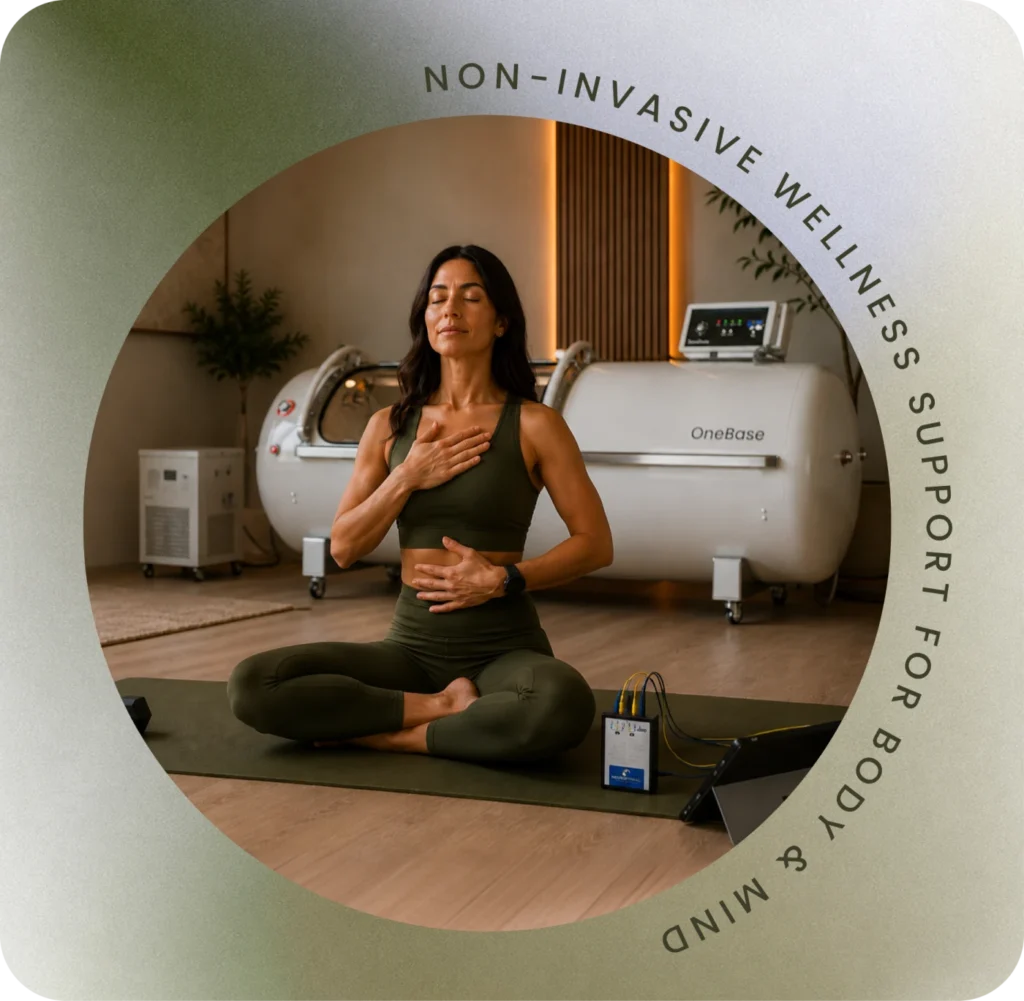 A guest practising calm breathwork beside the hyperbaric chamber and NeurOptimal® system at Restore Body & Mind Studio